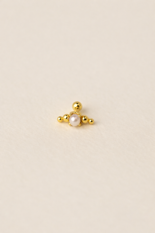 Gold earring with a central pearl on a beige background