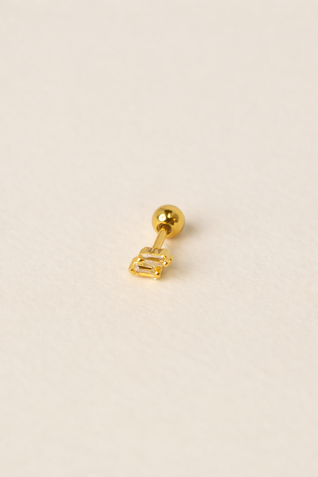 Gold earring on a beige background