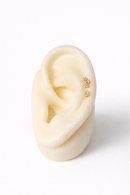 Close-up of an ear with gold earrings on a white background