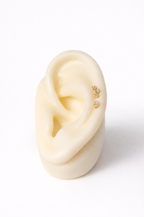 Close-up of an ear with gold earrings on a white background