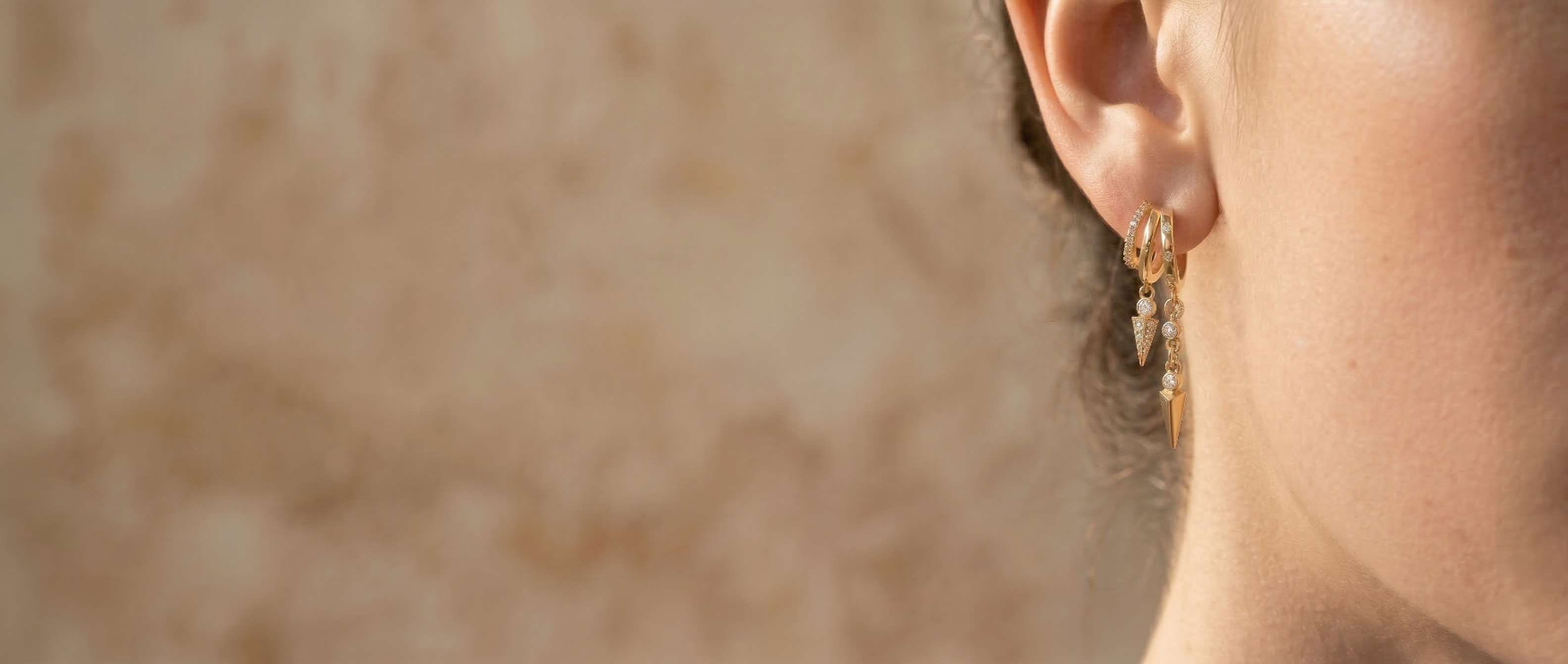 Close-up of a person wearing gold earrings with a blurred background
