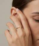 Close-up of a hand with a diamond ring on a neutral background