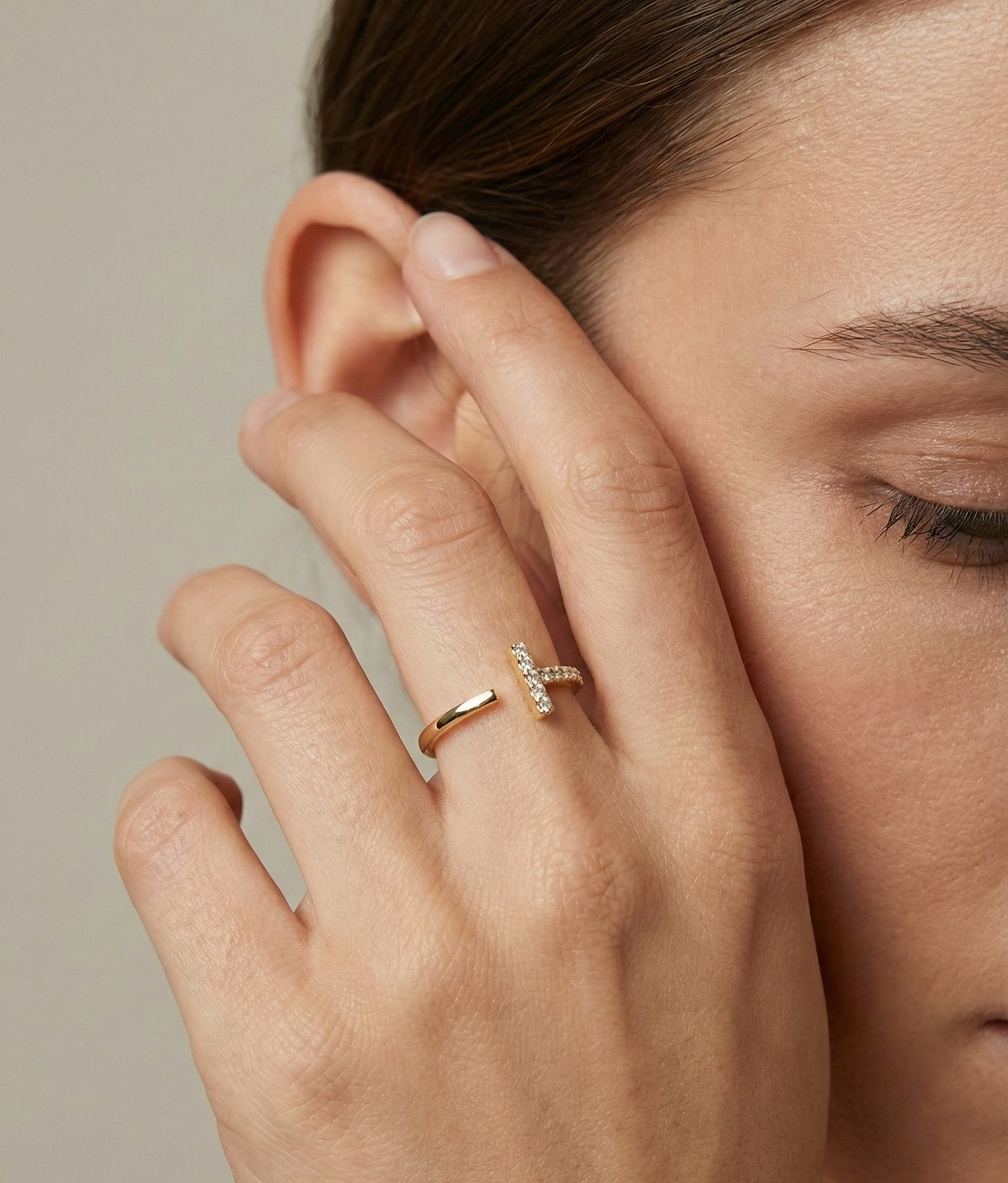 Close-up of a hand with a diamond ring on a neutral background